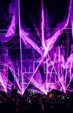 purple lights are projected over the crowd at an outdoor music festival in front of a black background