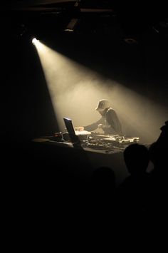 a dj playing music on his turntable in the dark