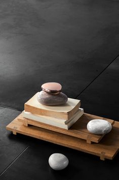 two rocks sitting on top of a wooden tray next to each other in front of a black wall