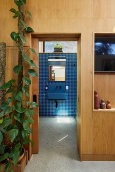 an open door leading to a bathroom with blue tiles on the walls and potted plants