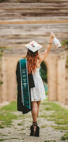 a woman in a graduation cap and gown is walking down a path with her diploma