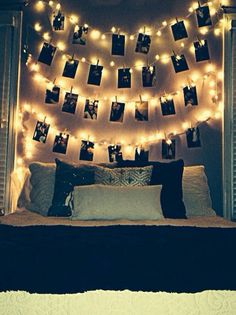 a bed with lights strung over it and pictures on the wall