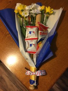 a bouquet of flowers is wrapped in paper and tied to a baseball bat on a table