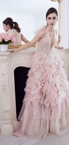 a woman standing in front of a mirror wearing a pink dress