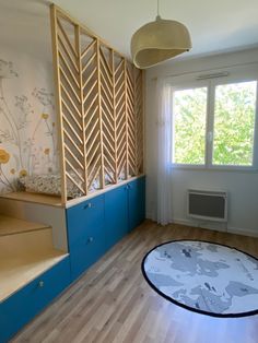 an empty room with blue cabinets and wooden flooring on the walls, along with a round rug