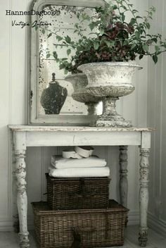 a white table topped with a mirror next to a basket filled with flowers and towels