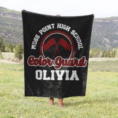 a person standing in a field holding a black towel with the words, moss point high school elder guard ollivia on it