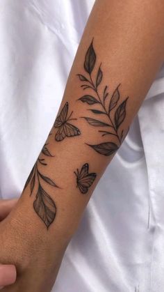 a woman's arm with tattoos on it and butterflies flying over the top of her arm