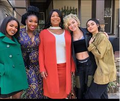 four women standing together in front of a house