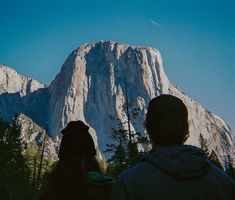 two people standing in front of a mountain