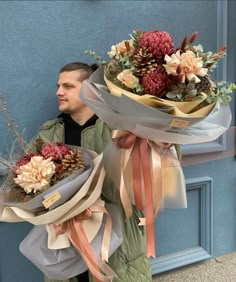 the man is holding two large bouquets of flowers