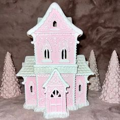 a pink and white doll house with trees in the back ground on a gray background