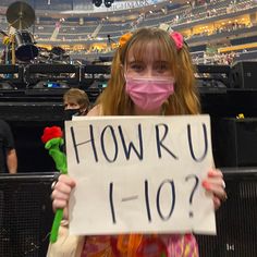 a girl wearing a face mask holding up a sign