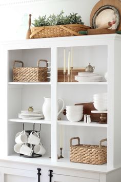 a white bookcase filled with dishes and baskets