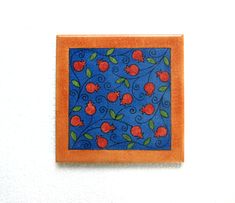 an orange and blue tile with red cherries on it, against a white wall