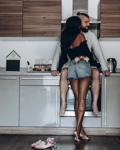 a man and woman sitting on top of each other in the kitchen