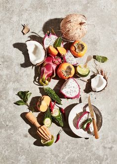 an assortment of fruits and vegetables on a concrete surface, including melon, radishes, kiwi, pears, oranges