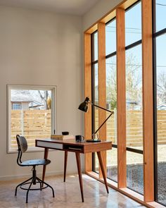 an office with large windows and a desk in front of the sliding glass doors that lead out to a back yard