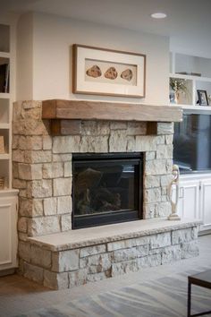 a living room with a stone fireplace and built in bookshelves