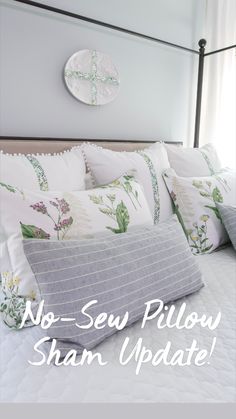 a bed with white and gray pillows and a cross on the wall above it's headboard