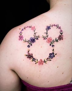 the back of a woman's shoulder with flowers in the shape of a heart