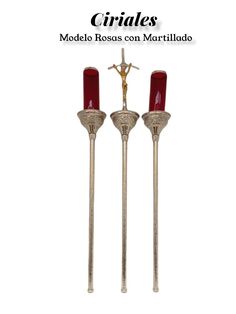 two metal candles with red candlesticks and a cross on the top of them