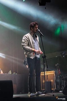 a man standing on top of a stage next to a microphone in front of him