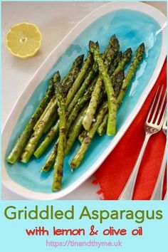 grilled asparagus with lemon and olive oil on a blue plate next to a fork