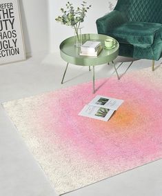 a living room with a green chair and a pink rug on the floor next to a coffee table