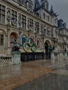 the olympic rings are on display in front of an old building with statues and flags