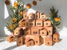 a pile of cardboard houses sitting on top of a table next to a christmas tree