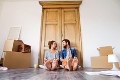 two people sitting on the floor in front of boxes