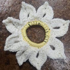 a white crocheted flower sitting on top of a rock