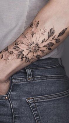 a woman's arm with flowers and leaves tattooed on the left side of her arm