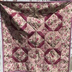 a pink and white quilt hanging from a clothes line