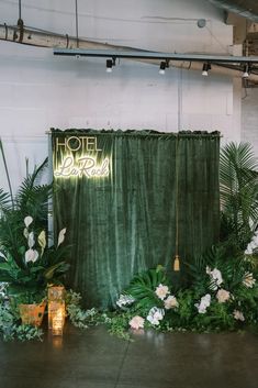 a green backdrop with white flowers and greenery in front of an open air space