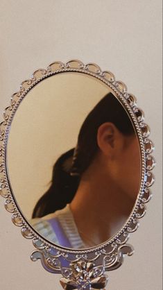 a woman's reflection in a round mirror on a stand with an ornate frame