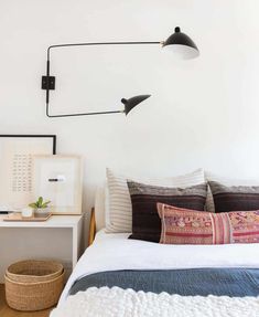 a bed with two lamps on the wall above it