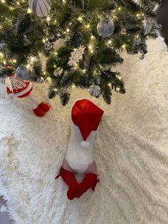 a small christmas tree with red and white stockings on it's feet next to a fake snowman