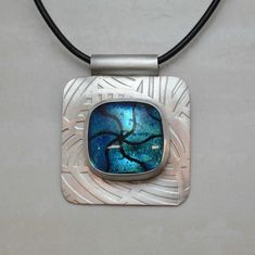 "Set within a fine silver bezel this colorful pendant has a dichroic glass cabochon that was created im my studio using multiple pieces of glass. Measuring about 1-1/8\" x 1-1/8\" the pendant is hand made in sterling and fine silver. A black leather neck cord is included with this pendant. Comes attractively gift boxed. For more details on shipping, packaging and returns see shipping and policies tab above. To return to the pendants and neck ware section: https://www.etsy.com/shop/MarkWhiteDesig Artsy Silver Jewelry With Large Pendant, Artistic Glass Jewelry Nickel-free, Artsy Silver Round Pendant Jewelry, Artsy Silver Pendant Jewelry, Handmade Glass Square Pendant Jewelry, Handmade Square Glass Pendant Jewelry, Fused Silver Jewelry, Glasses Jewelry, Fused Glass Jewelry Dichroic