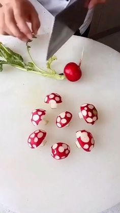 a person cutting up some food on top of a white table with radishes