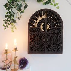 a wall mounted clock sitting on top of a wooden shelf next to two candle holders