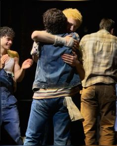 two men hugging each other while standing on stage