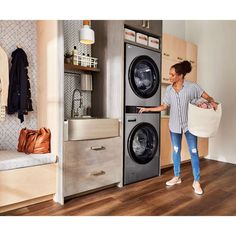 a woman holding a laundry bag in front of an open washer and dryer