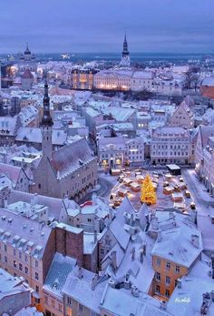 the city is covered in snow and lit up with christmas lights on it's rooftops