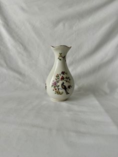 a white vase sitting on top of a white sheet