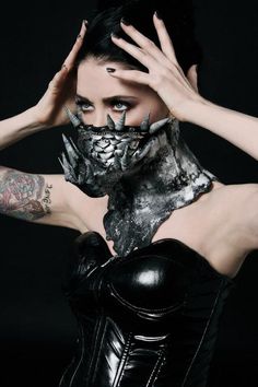 a woman with tattoos on her face and hands covering her face while posing for the camera