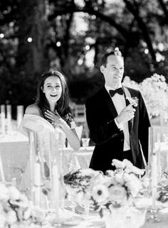 a man and woman standing next to each other at a table with flowers on it