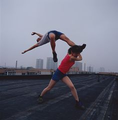 two people doing acrobatic tricks on a roof