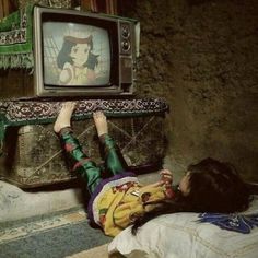 a woman laying on the ground in front of a tv with an image of snow white on it